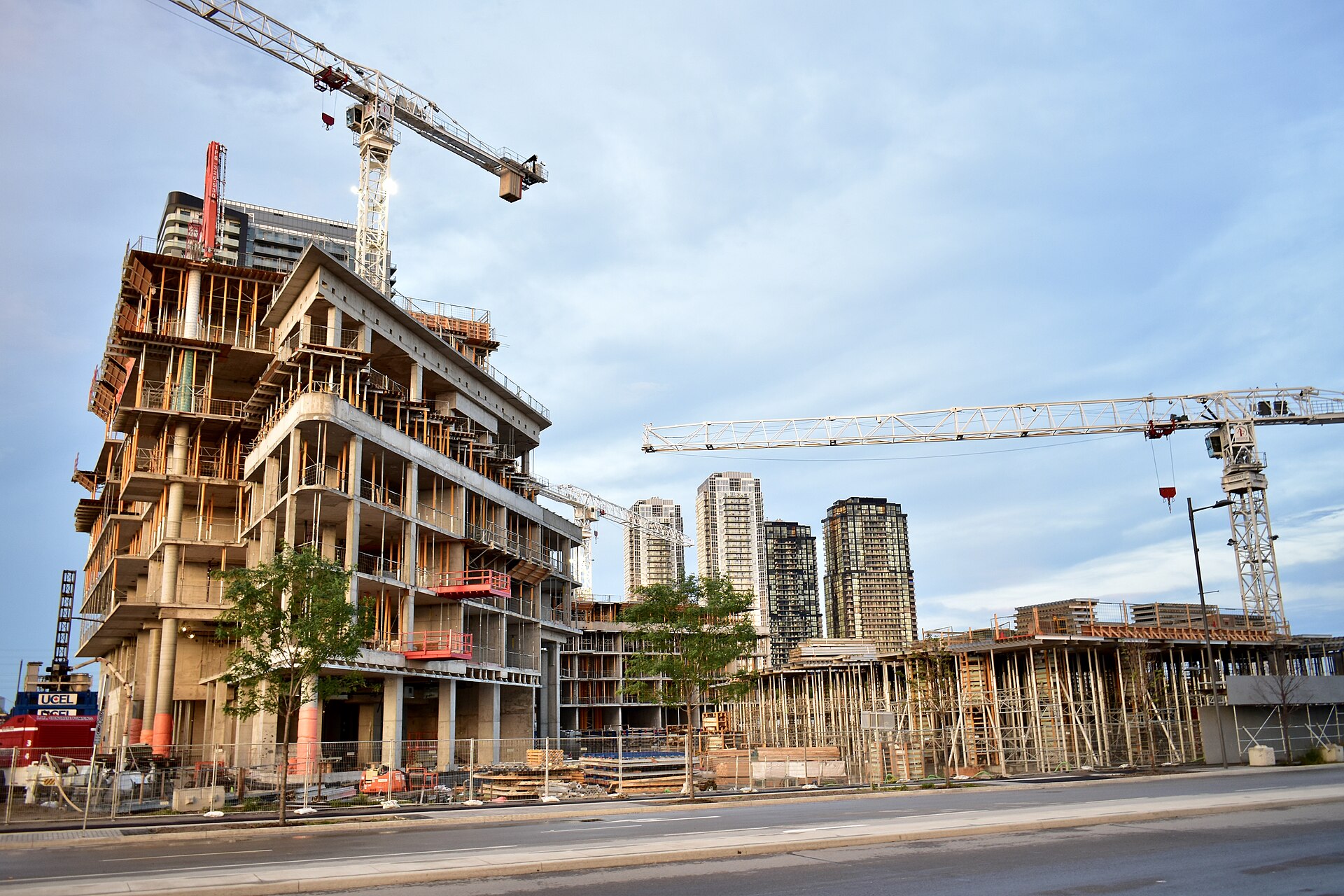 Tower cranes rising over a large urban construction site where new buildings are going up.