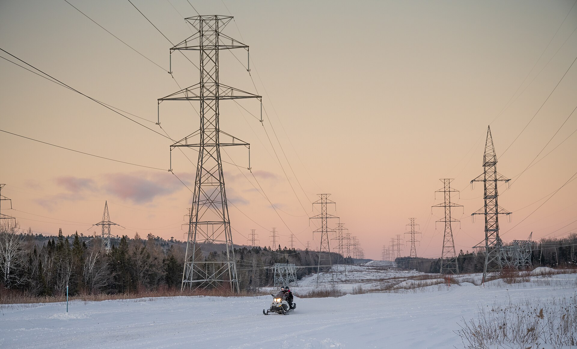 Electricity pylons and power lines silhouetted against a sunset sky in Quebec City